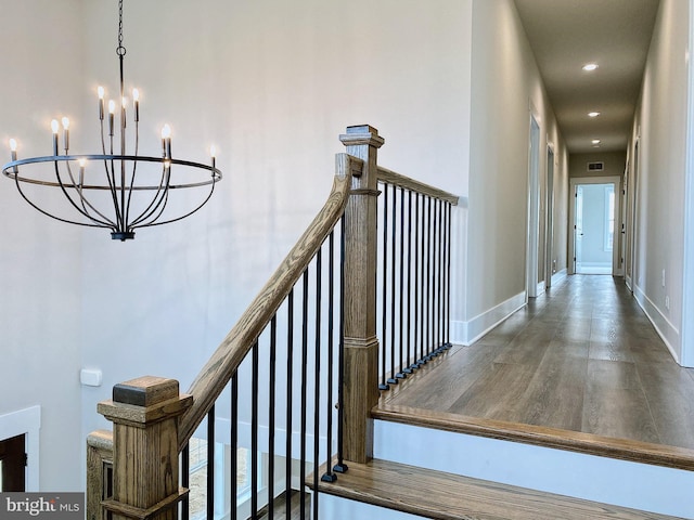 staircase with hardwood / wood-style floors and a chandelier