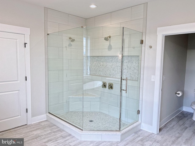 bathroom with toilet, hardwood / wood-style flooring, and walk in shower