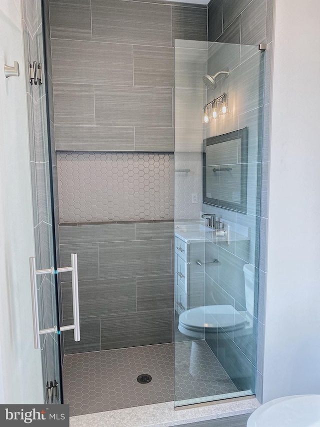 bathroom featuring vanity, toilet, and tiled shower