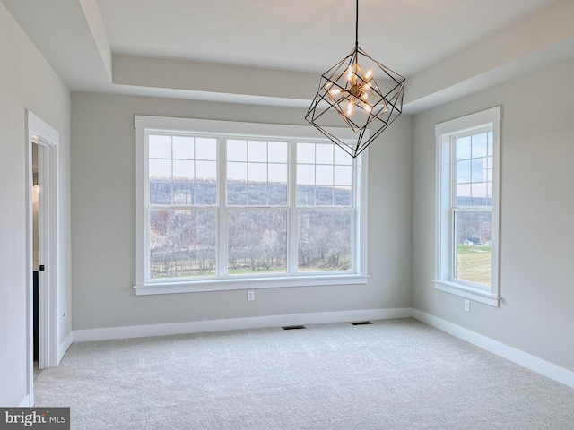 unfurnished dining area with a wealth of natural light, a chandelier, and carpet