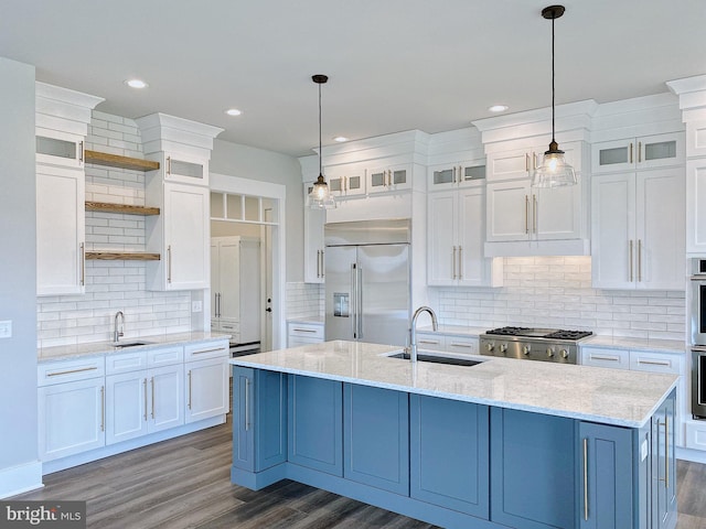 kitchen featuring an island with sink, sink, white cabinets, pendant lighting, and appliances with stainless steel finishes