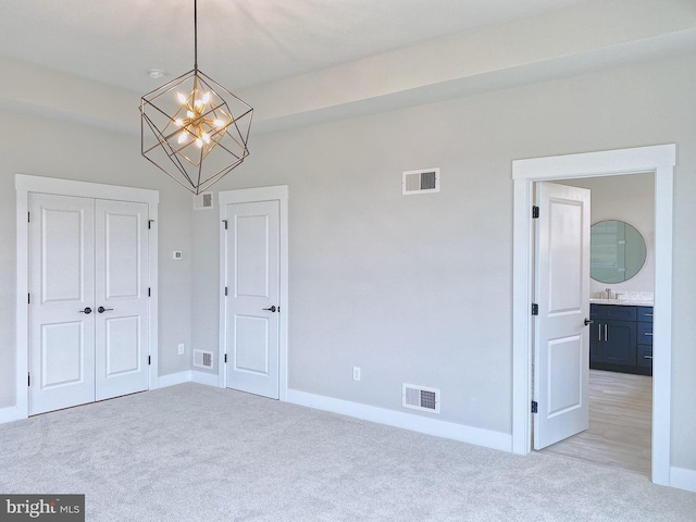 unfurnished bedroom featuring sink, light carpet, a closet, and ensuite bath