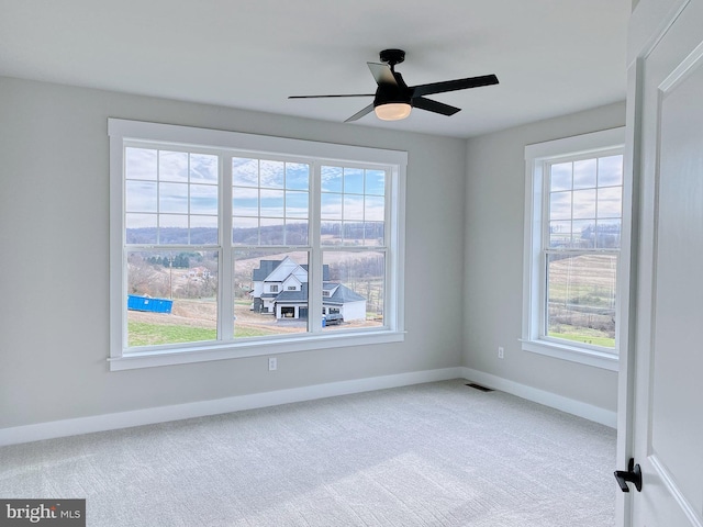 carpeted empty room with a wealth of natural light and ceiling fan