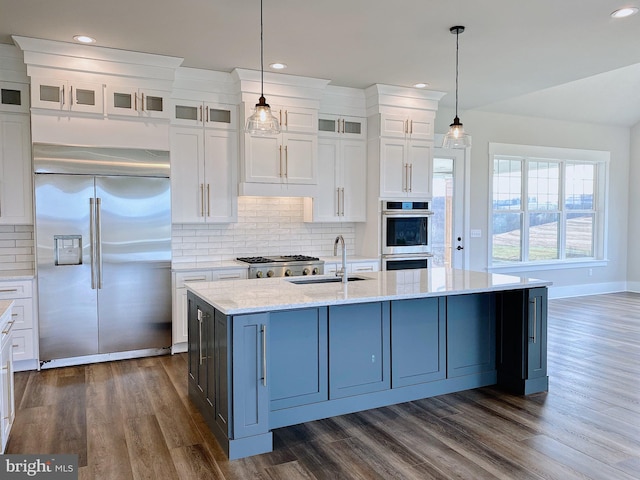 kitchen featuring white cabinets, hanging light fixtures, backsplash, appliances with stainless steel finishes, and sink