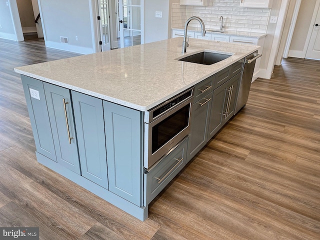 kitchen with a kitchen island with sink, sink, and dark wood-type flooring