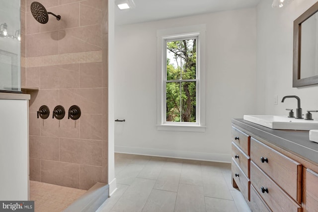 bathroom with vanity, a tile shower, and tile patterned floors