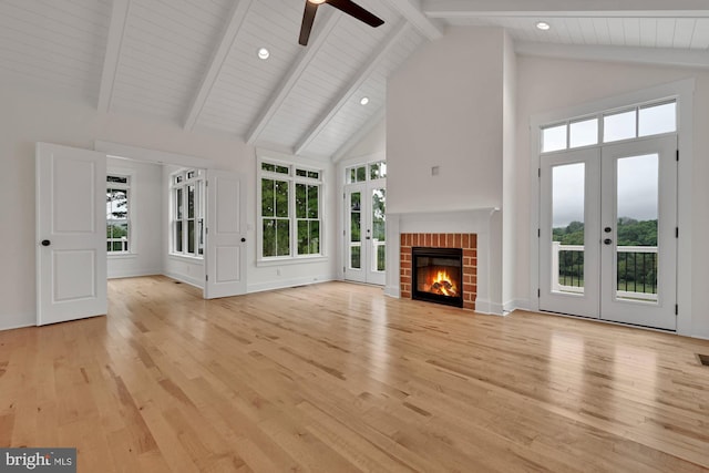 unfurnished living room with french doors, light wood-type flooring, high vaulted ceiling, and plenty of natural light