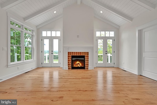 unfurnished living room featuring light hardwood / wood-style flooring, french doors, plenty of natural light, and a brick fireplace