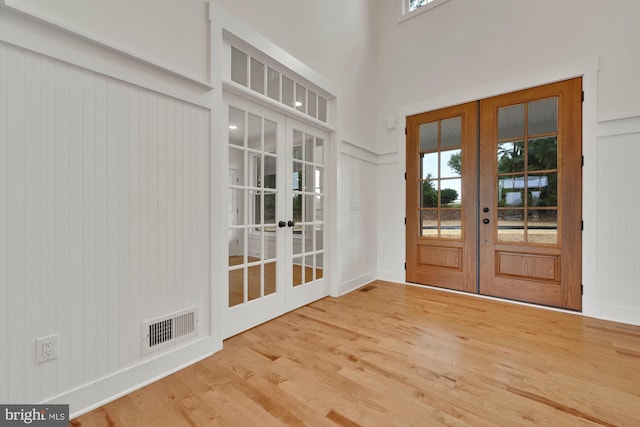 entryway featuring light hardwood / wood-style flooring, french doors, and a high ceiling