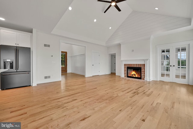 unfurnished living room with light hardwood / wood-style floors, high vaulted ceiling, and a fireplace