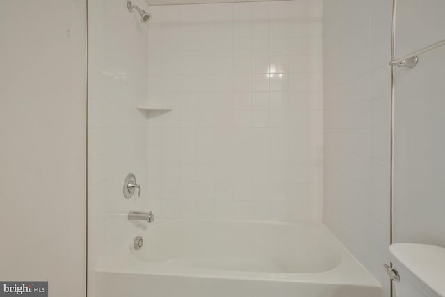 bathroom featuring toilet and tiled shower / bath