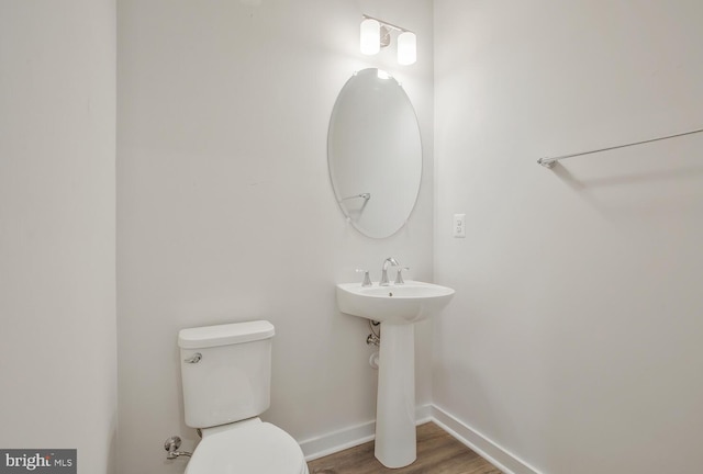 bathroom with toilet, wood-type flooring, and sink