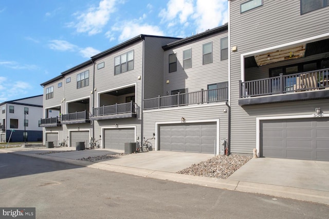 exterior space with cooling unit, a balcony, and a garage