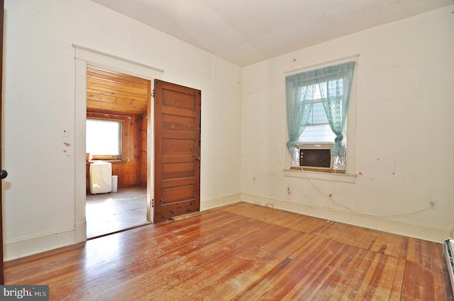 spare room featuring baseboard heating and wood-type flooring