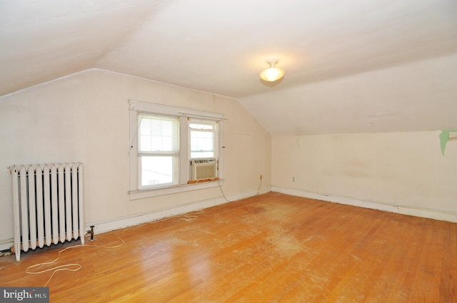 bonus room featuring vaulted ceiling, cooling unit, radiator heating unit, and hardwood / wood-style floors