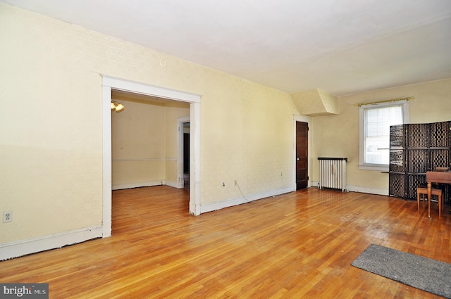 unfurnished living room featuring radiator and light wood-type flooring