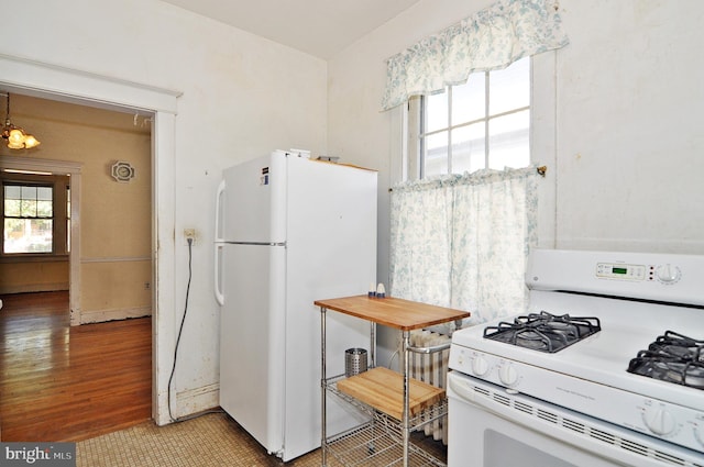 kitchen featuring white appliances, a notable chandelier, and light hardwood / wood-style flooring