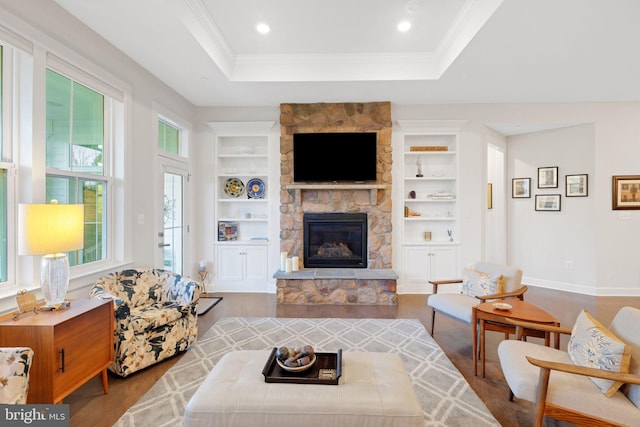 living room featuring a fireplace, light hardwood / wood-style flooring, a healthy amount of sunlight, and built in features