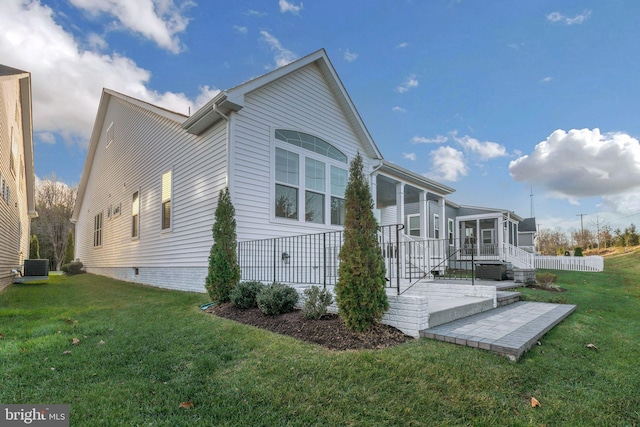 view of property exterior with a sunroom, cooling unit, and a yard