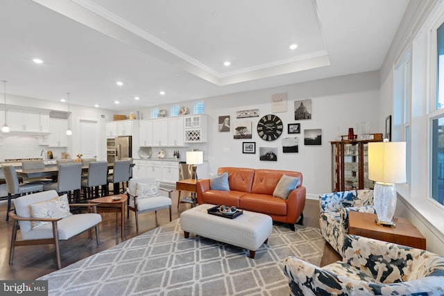 living room with hardwood / wood-style flooring, crown molding, and a tray ceiling