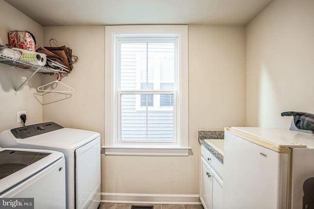 clothes washing area with washer and dryer, cabinets, and light tile patterned floors