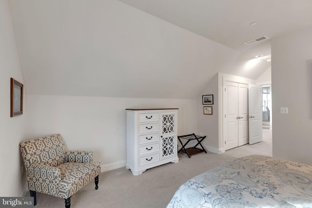 bedroom with vaulted ceiling, light carpet, and a closet