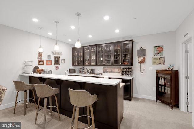 bar with pendant lighting, dark brown cabinetry, and light carpet