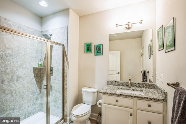 bathroom with vanity, toilet, and a shower with door