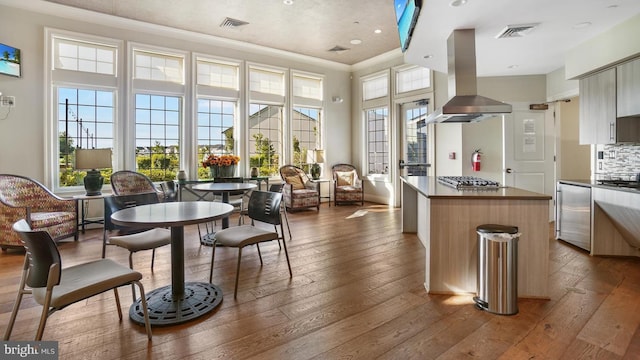 kitchen with backsplash, island range hood, a kitchen island, and light hardwood / wood-style floors