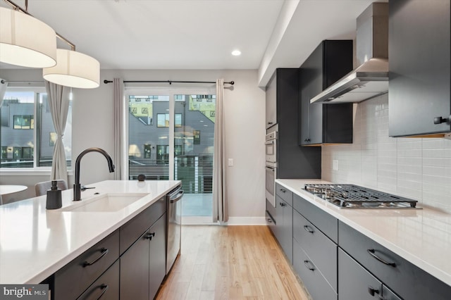 674 N 13th St, Philadelphia, PA 19123 - kitchen with a sink, stainless steel appliances, light countertops, light wood-type flooring, and wall chimney exhaust hood