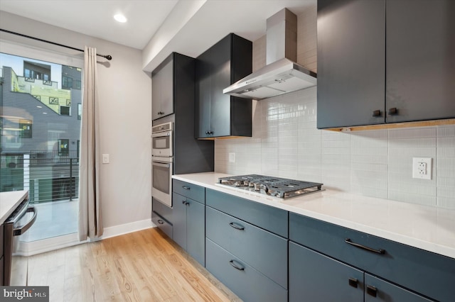 674 N 13th St, Philadelphia, PA 19123 - kitchen with stainless steel appliances, wall chimney exhaust hood, backsplash, light wood-style flooring, and light countertops