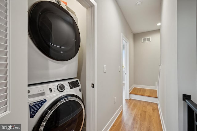 laundry area featuring light wood-type flooring and stacked washer and clothes dryer