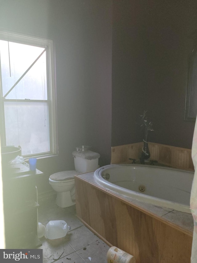 bathroom with tile patterned flooring, a washtub, and toilet