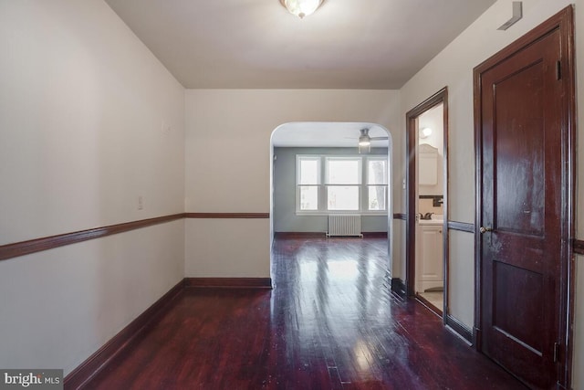 spare room with ceiling fan, radiator, and dark hardwood / wood-style flooring