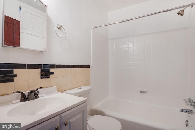 full bathroom featuring vanity, tiled shower / bath combo, toilet, and tile walls