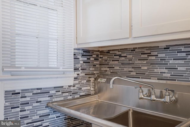 details with sink, white cabinetry, and decorative backsplash