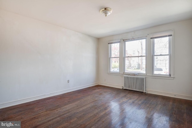 unfurnished room featuring dark hardwood / wood-style floors, radiator, and plenty of natural light