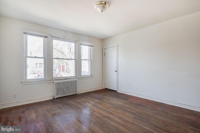 empty room with radiator heating unit and dark hardwood / wood-style floors