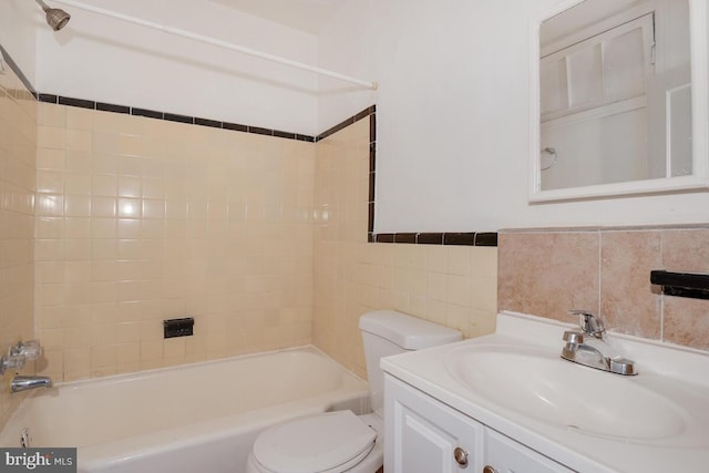 full bathroom with toilet, tiled shower / bath, vanity, and tile walls