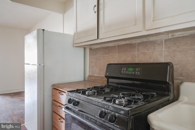 kitchen featuring black range with gas cooktop, decorative backsplash, and hardwood / wood-style floors