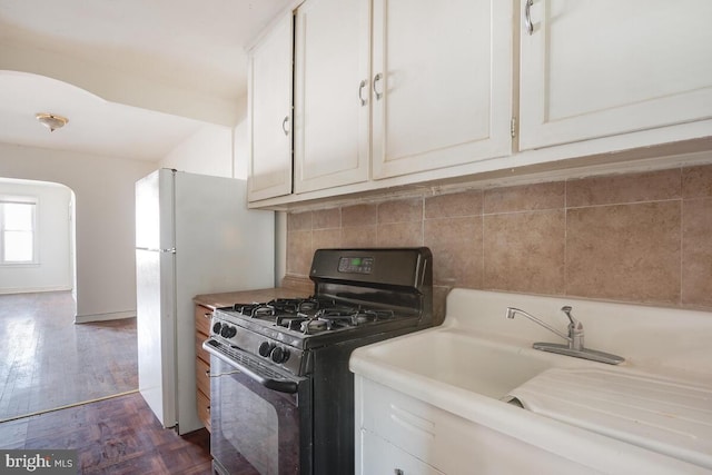 kitchen with black gas range, decorative backsplash, white cabinetry, and dark hardwood / wood-style floors