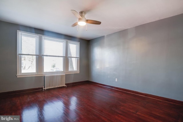 spare room featuring dark hardwood / wood-style flooring, ceiling fan, and radiator