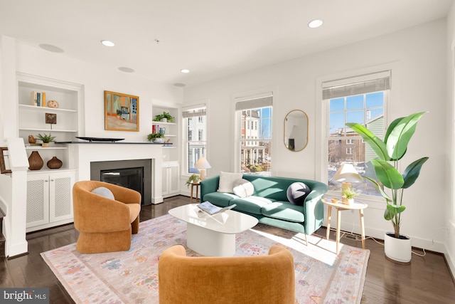 living room with built in shelves and dark wood-type flooring