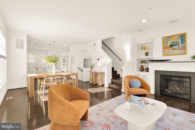 living room with built in features and dark wood-type flooring