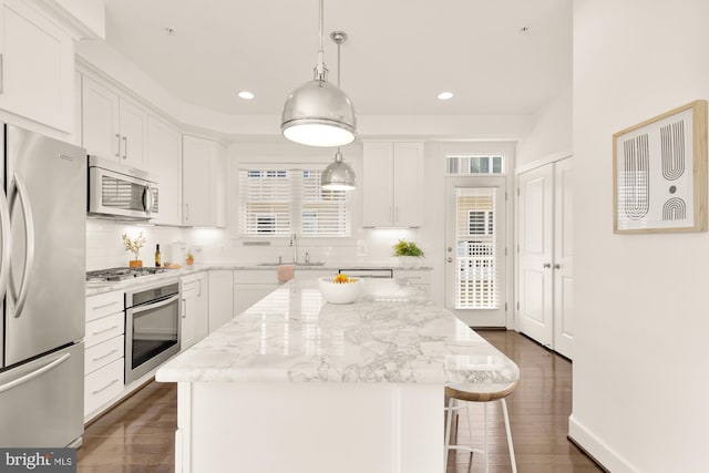 kitchen with white cabinets, a kitchen island, stainless steel appliances, and pendant lighting