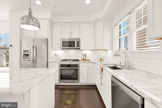 kitchen featuring white cabinets, stainless steel appliances, hanging light fixtures, and sink