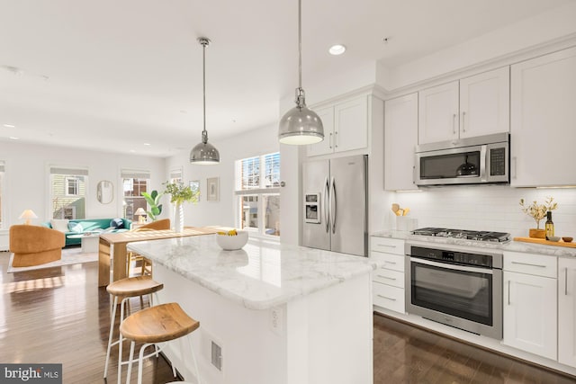 kitchen featuring white cabinetry, stainless steel appliances, decorative light fixtures, decorative backsplash, and a kitchen island