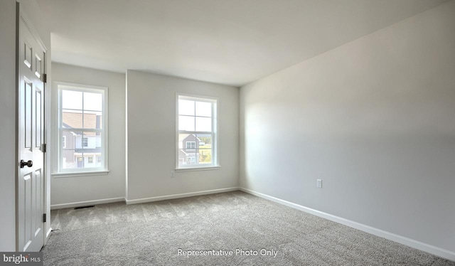 carpeted spare room featuring plenty of natural light