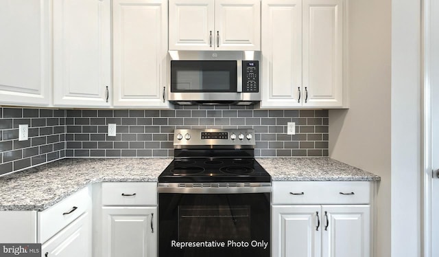 kitchen with light stone countertops, stainless steel appliances, white cabinetry, and tasteful backsplash