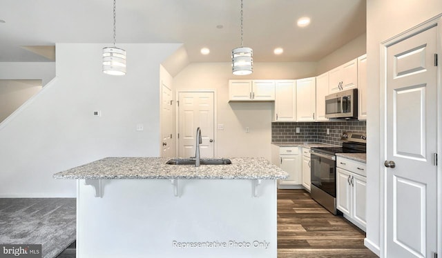 kitchen with light stone countertops, sink, stainless steel appliances, an island with sink, and white cabinets